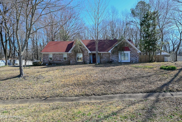 view of front of home with a chimney, fence, and brick siding