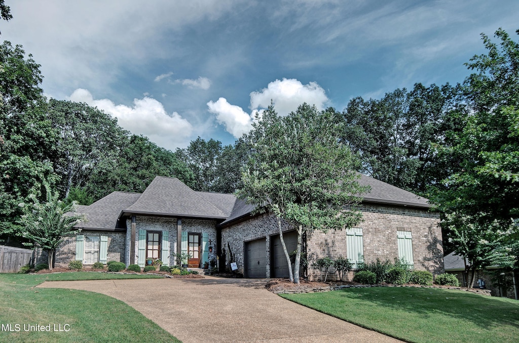 french provincial home featuring a front lawn and a garage