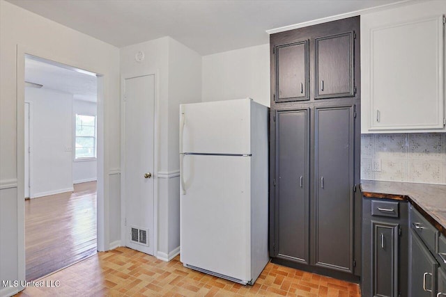 722 SE 1st St, Magee, MS 39111 - kitchen featuring decorative backsplash, visible vents, baseboards, freestanding refrigerator, and brick floor