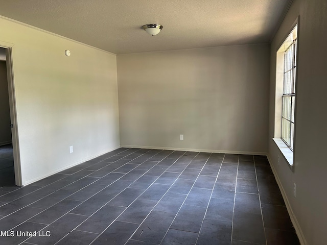 empty room with dark tile patterned flooring and a textured ceiling