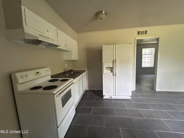 kitchen featuring white cabinetry, dark tile patterned floors, crown molding, sink, and white appliances