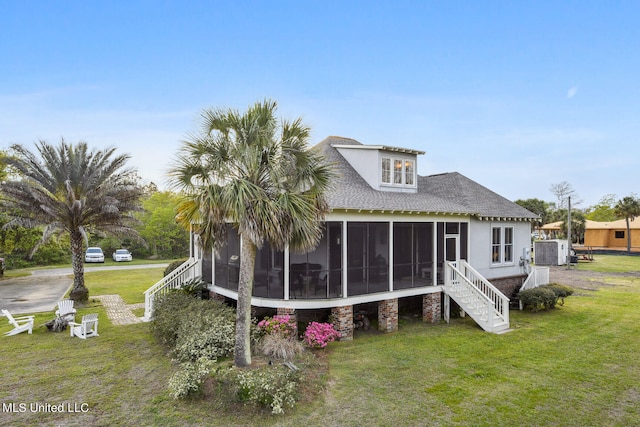 back of property with a sunroom and a lawn