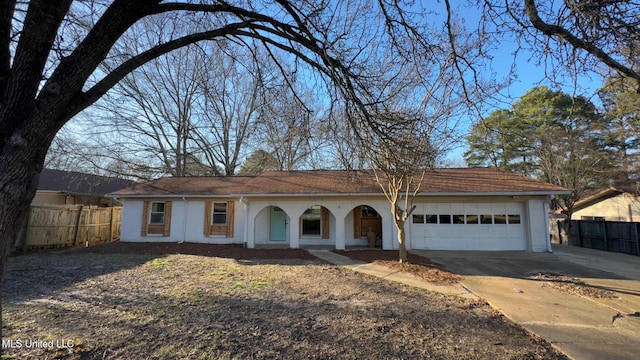 ranch-style home with concrete driveway, brick siding, an attached garage, and fence