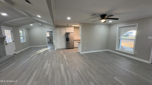 unfurnished living room with lofted ceiling with beams, wood finished floors, visible vents, baseboards, and ornamental molding