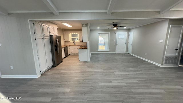 kitchen with open floor plan, beamed ceiling, light wood-type flooring, and stainless steel fridge with ice dispenser