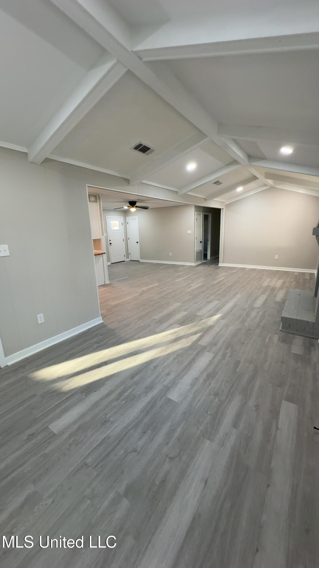 unfurnished living room featuring ceiling fan, vaulted ceiling with beams, baseboards, and wood finished floors