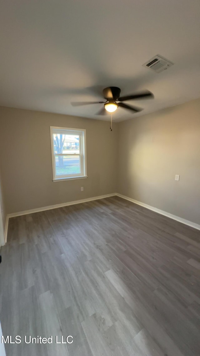 unfurnished room with a ceiling fan, wood finished floors, visible vents, and baseboards