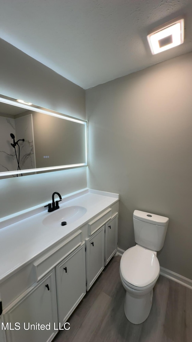 bathroom featuring toilet, wood finished floors, vanity, and baseboards