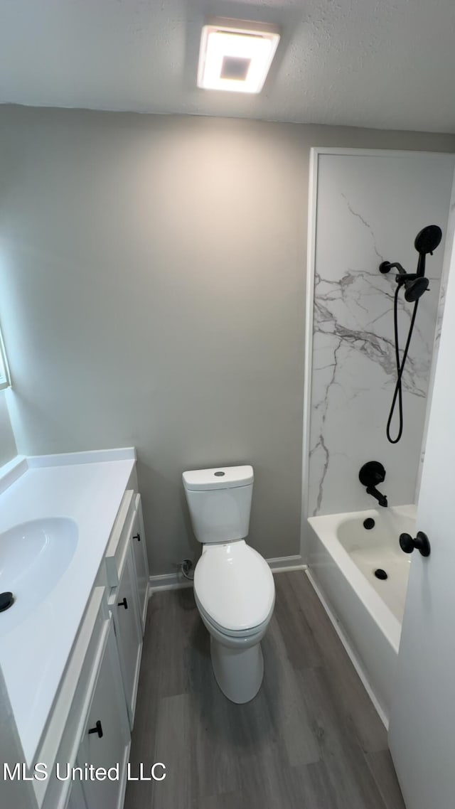 bathroom featuring toilet, baseboards, wood finished floors, and vanity