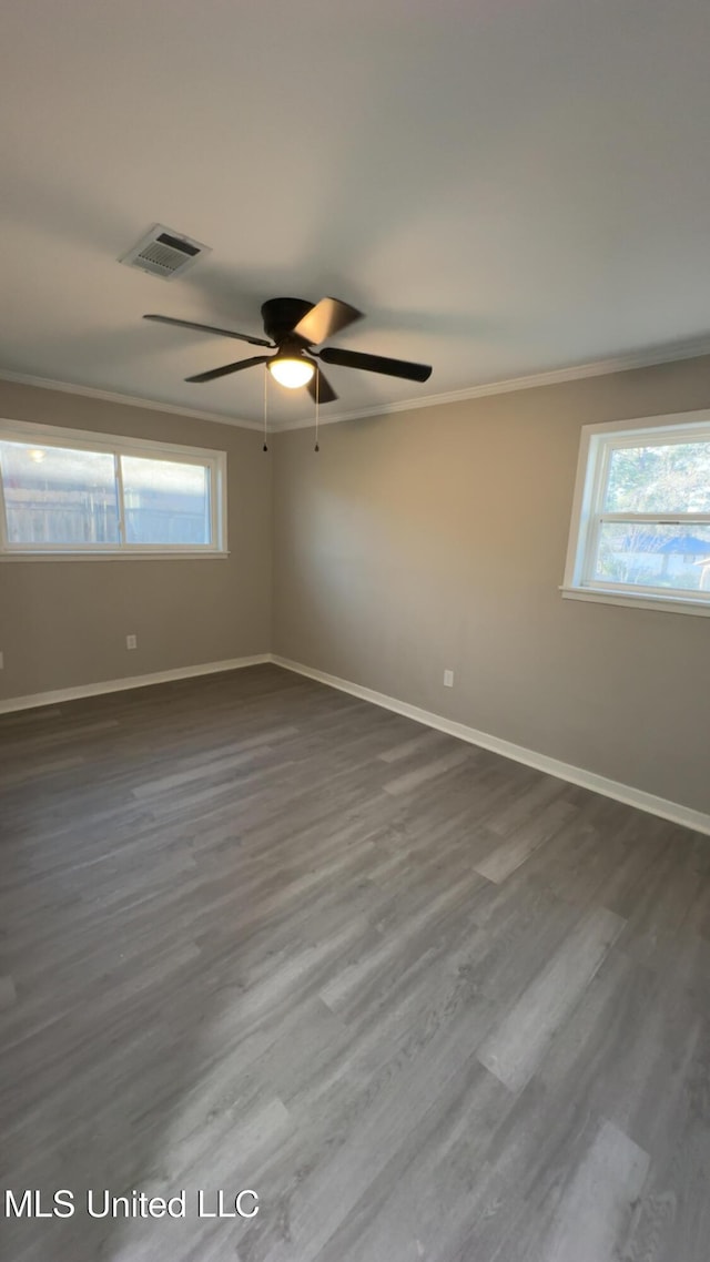 empty room featuring baseboards, dark wood-style flooring, visible vents, and crown molding