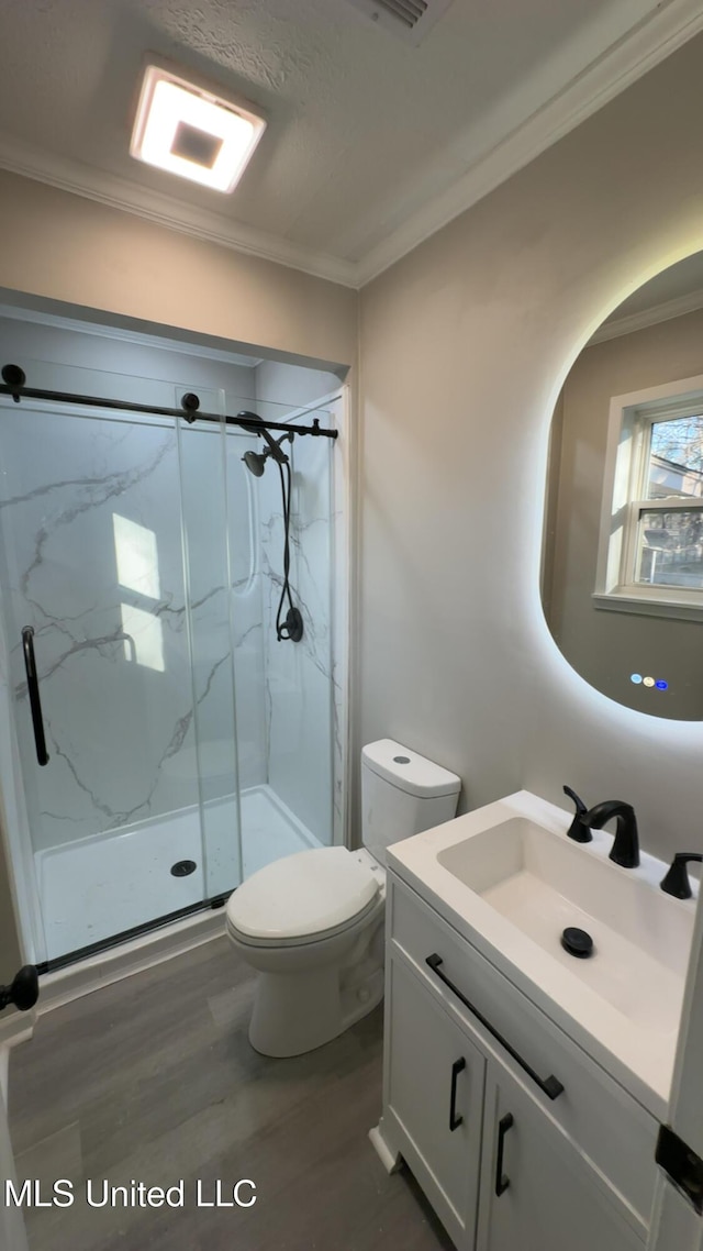 bathroom featuring a marble finish shower, crown molding, vanity, and toilet