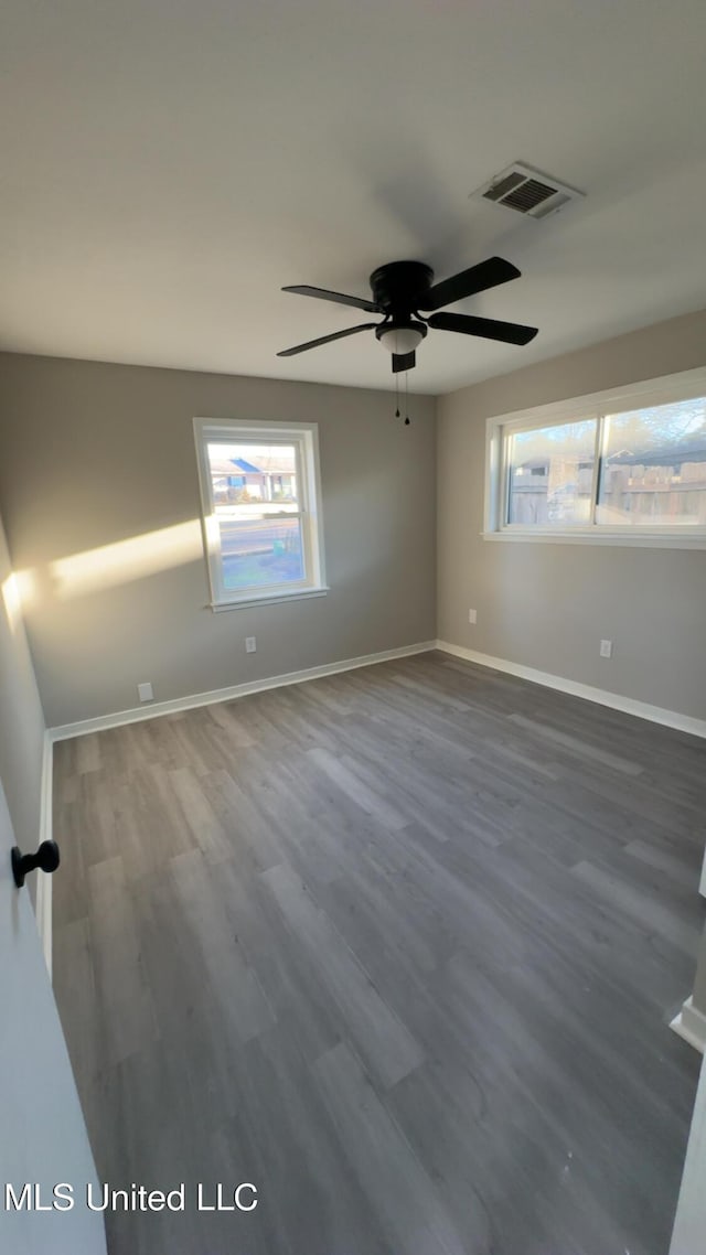 spare room featuring baseboards, visible vents, a wealth of natural light, and wood finished floors