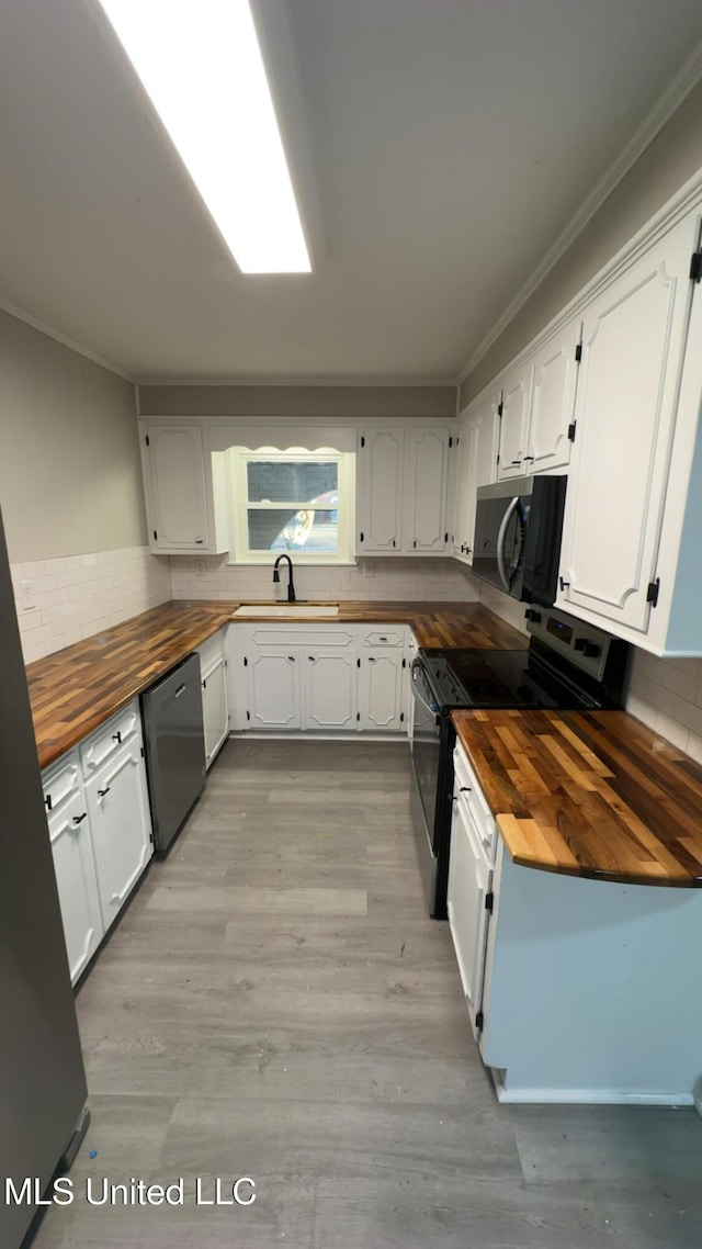 kitchen with butcher block counters, electric range, decorative backsplash, stainless steel dishwasher, and a sink