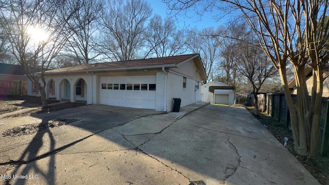 view of property exterior with a garage, brick siding, fence, and driveway