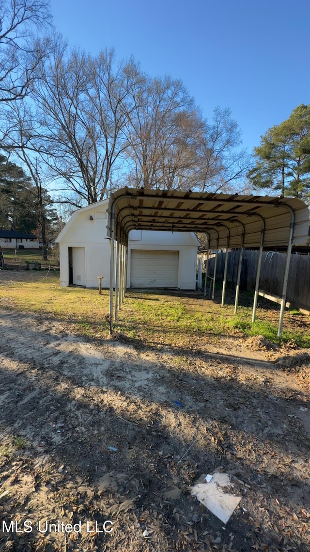 view of outdoor structure with a carport, an outdoor structure, and fence