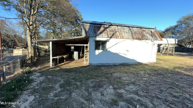 rear view of house with fence, metal roof, and an outbuilding