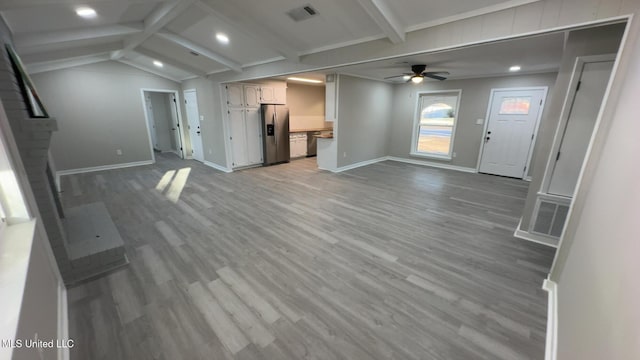 unfurnished living room with vaulted ceiling with beams, ceiling fan, light wood-style flooring, visible vents, and baseboards