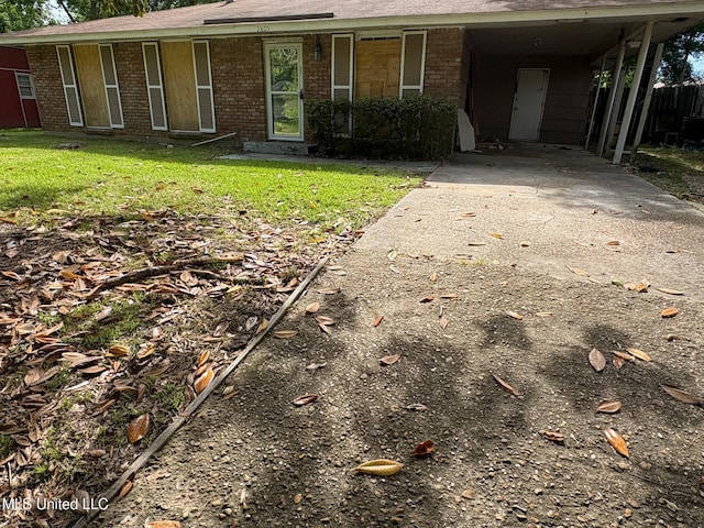 view of front facade featuring an attached carport, brick siding, driveway, and a front lawn