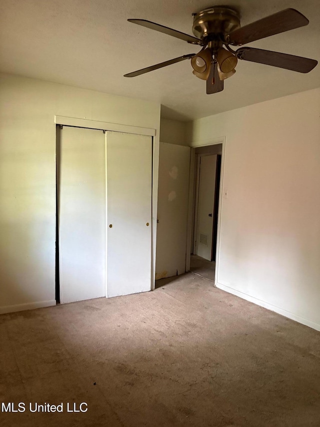 unfurnished bedroom featuring baseboards, ceiling fan, carpet, and a closet