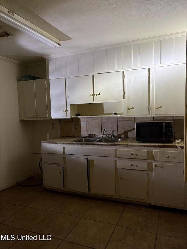 kitchen with light countertops, white cabinetry, tile patterned floors, and a sink