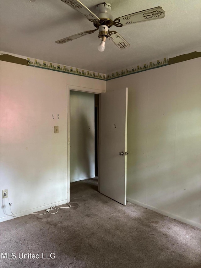 carpeted spare room featuring baseboards and ceiling fan