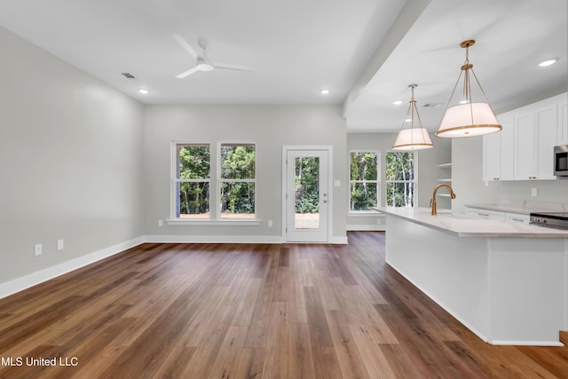 13379 Wash Fayard Rd, Biloxi, MS 39532 - kitchen with stainless steel microwave, light countertops, dark wood-type flooring, white cabinetry, and recessed lighting