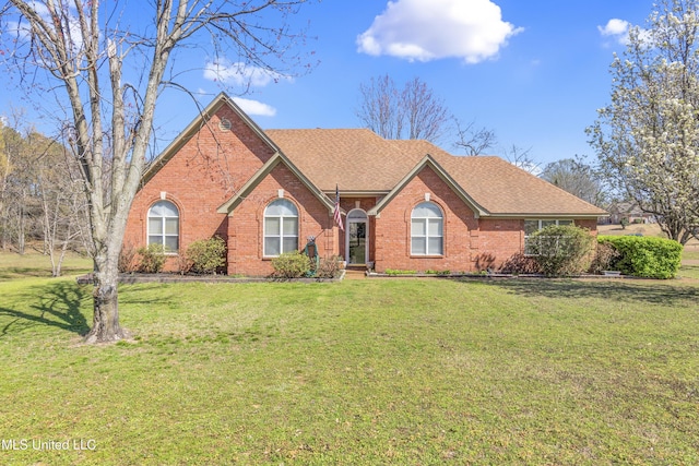 ranch-style home featuring brick siding, a shingled roof, and a front lawn
