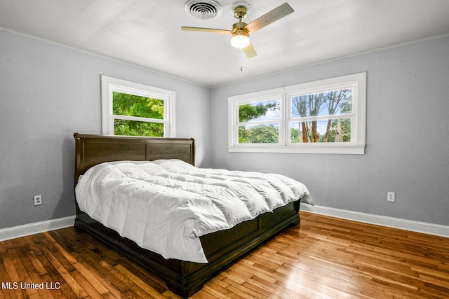 bedroom featuring crown molding, wood-type flooring, and ceiling fan