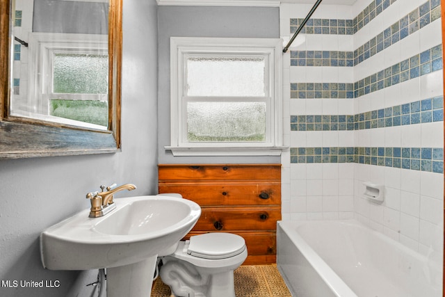 bathroom featuring toilet, plenty of natural light, and tiled shower / bath