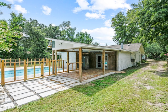 back of property featuring a lawn, a patio, a fenced in pool, and ceiling fan