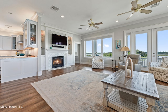 living room with a premium fireplace, crown molding, ceiling fan, and dark hardwood / wood-style flooring