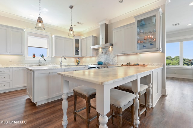 kitchen with wall chimney exhaust hood, a kitchen island, white cabinetry, and dark hardwood / wood-style flooring