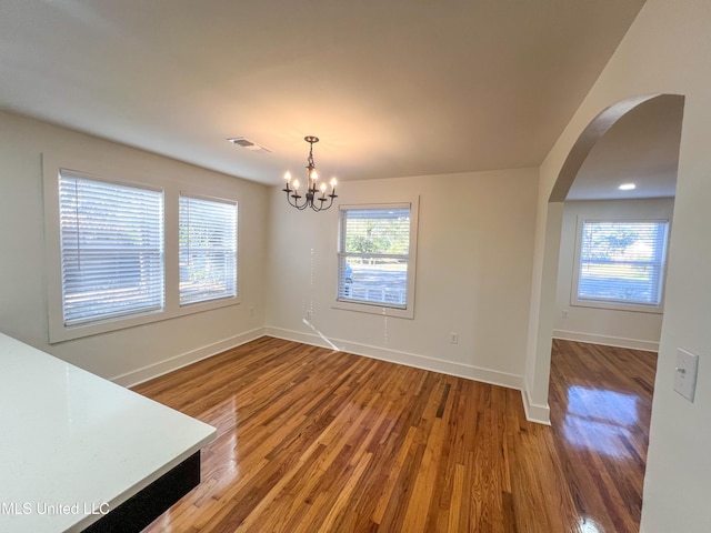 unfurnished dining area featuring hardwood / wood-style floors and a notable chandelier