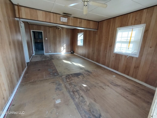 unfurnished room with ceiling fan and wooden walls