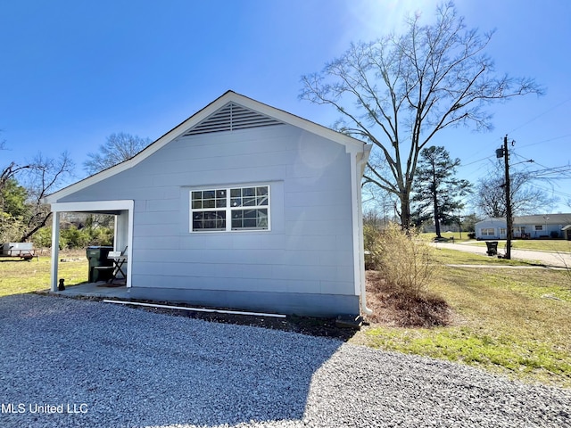 view of side of home with an outdoor structure and gravel driveway