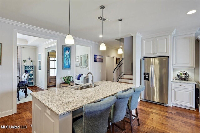 38 Savannah Cir, Brandon, MS 39047 - kitchen with stainless steel fridge, crown molding, white cabinets, light stone countertops, and an island with sink