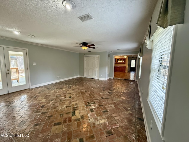unfurnished room with visible vents, ornamental molding, brick floor, baseboards, and ceiling fan
