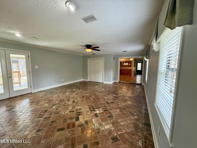 unfurnished room featuring crown molding, a textured ceiling, ceiling fan, baseboards, and visible vents