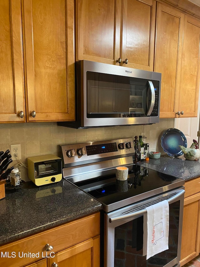 kitchen with backsplash, stainless steel appliances, and dark stone counters