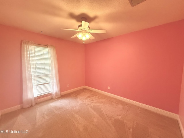 carpeted spare room featuring ceiling fan and baseboards