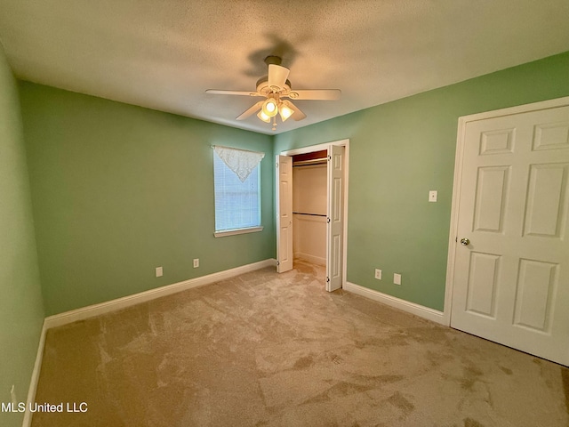 unfurnished bedroom featuring a ceiling fan, a textured ceiling, a closet, carpet floors, and baseboards