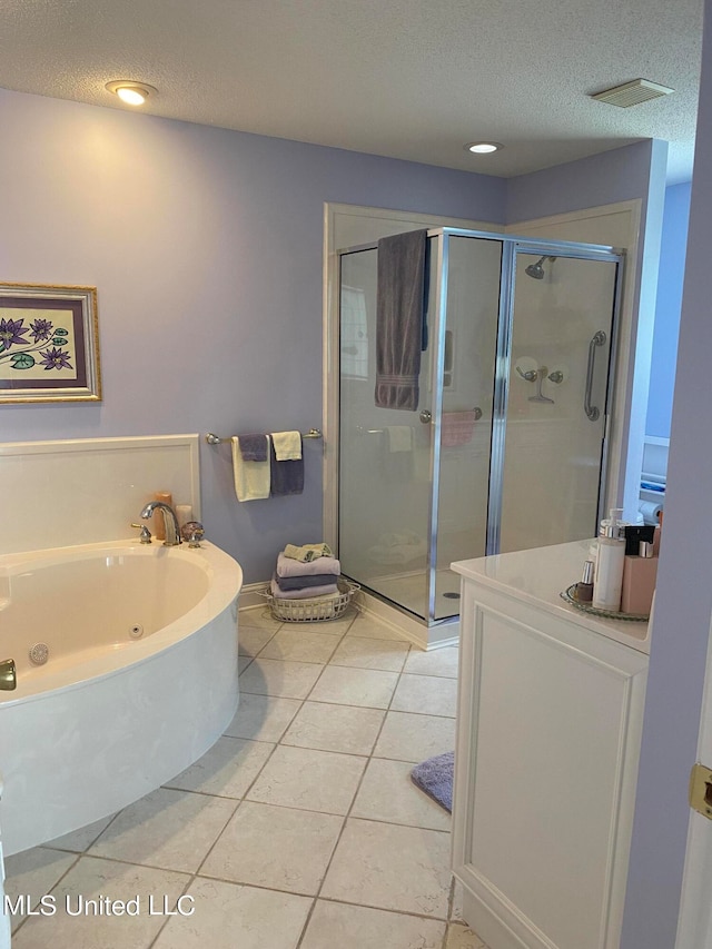 bathroom featuring plus walk in shower, vanity, a textured ceiling, and tile patterned flooring