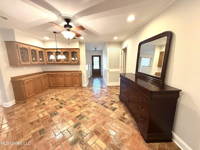 kitchen featuring glass insert cabinets, baseboards, brown cabinets, and ceiling fan