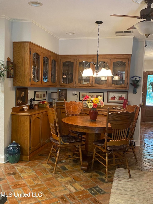 dining space with ceiling fan with notable chandelier and ornamental molding