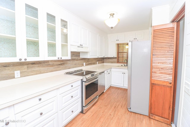 206 Oak Park Dr, Pearl, MS 39208 - kitchen featuring appliances with stainless steel finishes, light countertops, white cabinetry, light wood finished floors, and glass insert cabinets