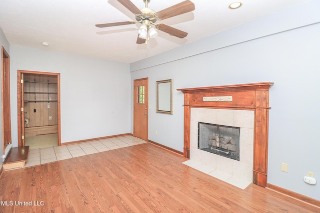 206 Oak Park Dr, Pearl, MS 39208 - unfurnished living room with wood finished floors, a tiled fireplace, and a ceiling fan