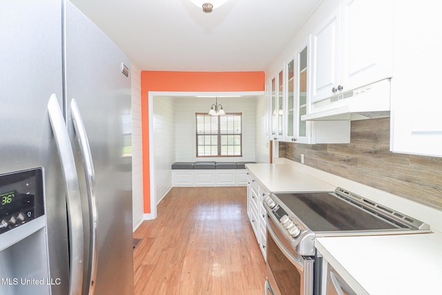 206 Oak Park Dr, Pearl, MS 39208 - kitchen featuring appliances with stainless steel finishes, under cabinet range hood, white cabinets, a chandelier, and glass insert cabinets