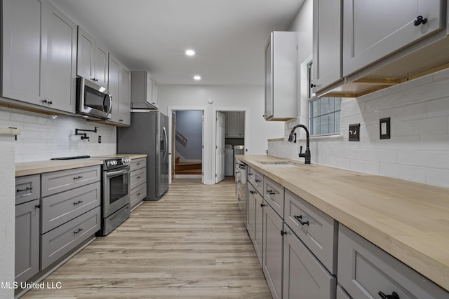 8839 Moanalua Way, Diamondhead, MS 39525 - kitchen with appliances with stainless steel finishes, gray cabinetry, washing machine and dryer, butcher block counters, and recessed lighting