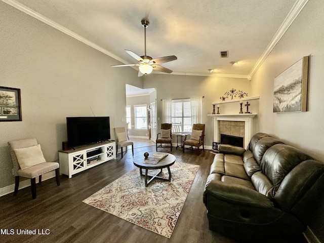 living room featuring dark hardwood / wood-style flooring, a tiled fireplace, vaulted ceiling, and ornamental molding