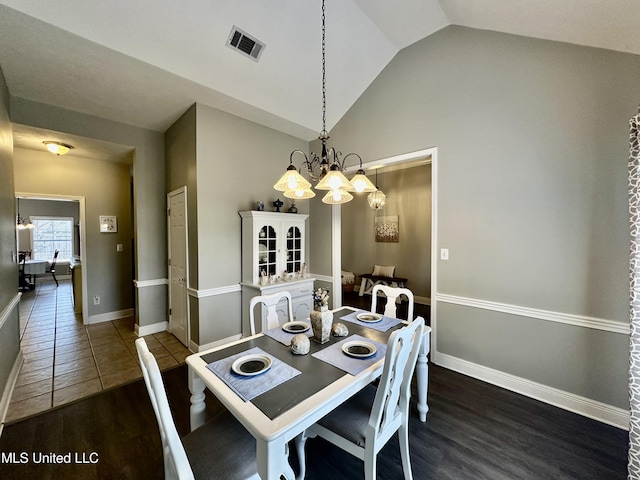 dining area featuring vaulted ceiling, dark wood-type flooring, and a chandelier